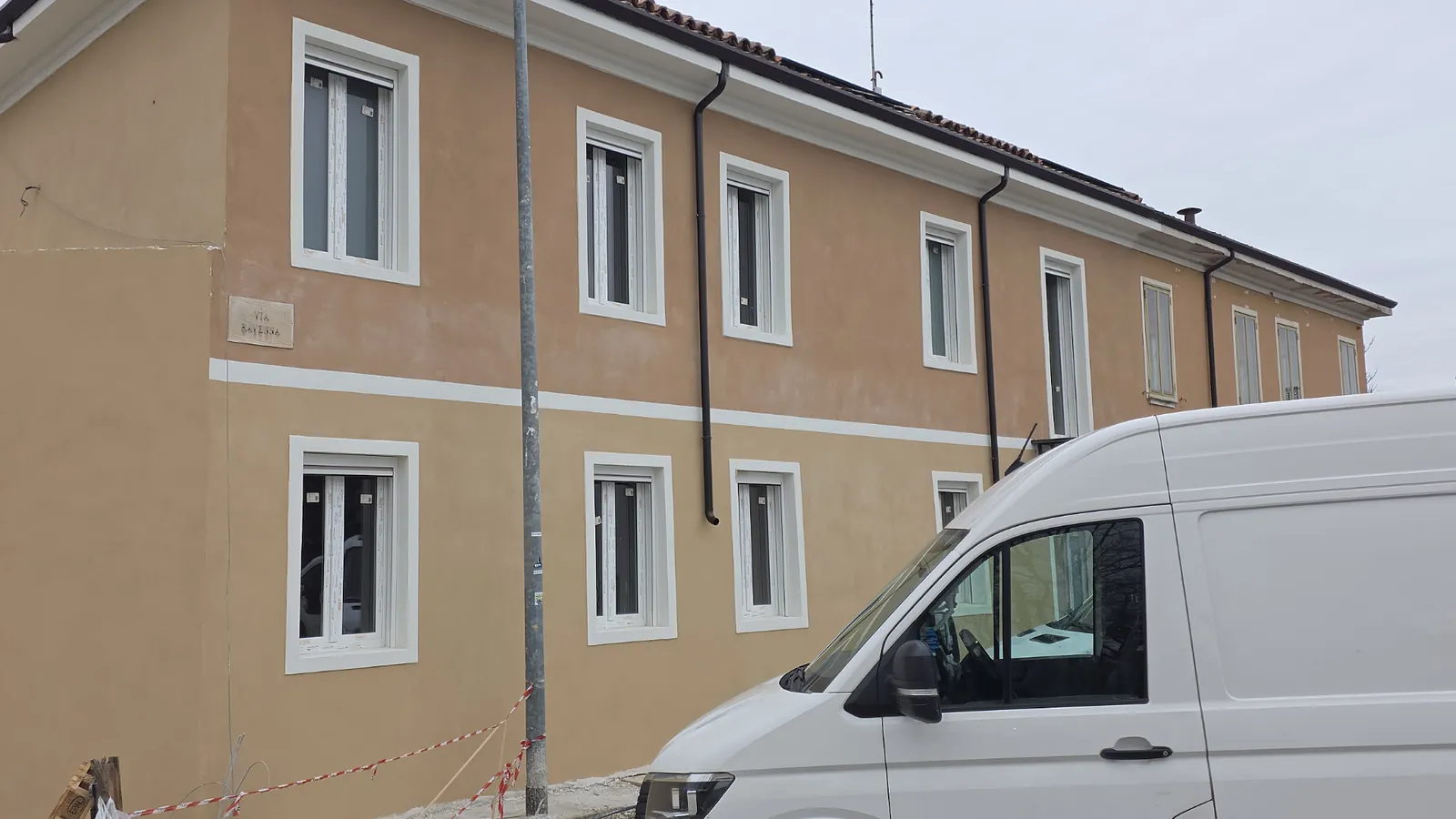 Edificio a due piani con finestre bianche su facciata ocra